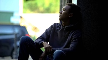 Karanlıkta oturup ilişki çatışmasını ve aileyi düşünen üzgün bir genç.