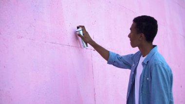 Afro-Amerikalı genç erkek sokak duvarına grafiti çiziyor, modern sanat.
