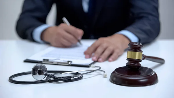Tuomari Allekirjoittaa Pidätysmääräyksen Lääketieteellisestä Virheestä Nuijan Hakkaamisesta Läheltä Stetoskooppia — kuvapankkivalokuva