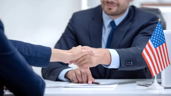 US official signing contract for international cooperation, shaking partner hand