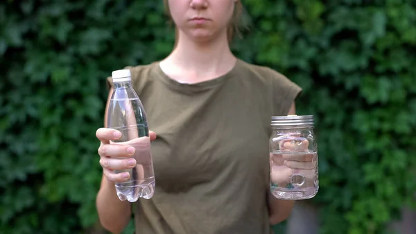 ガラスマグカップとペットボトルのどちらかを選ぶ女性 環境を救う — ストック写真