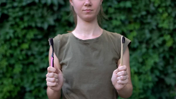 プラスチックと木製の歯ブラシの間の女性の選択 意識的な選択 — ストック写真