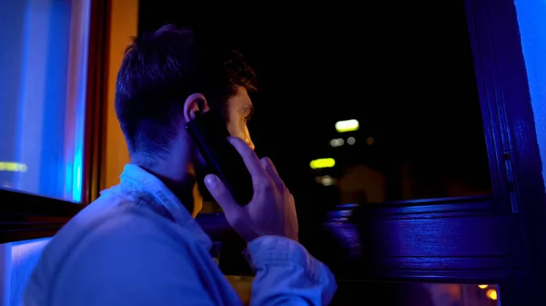 Droevige Man Aan Telefoon Kijkend Door Het Raam Wachtend Vrouw — Stockfoto
