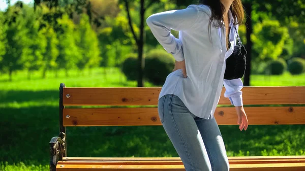 Young female feeling back pain outdoors, kidneys inflammation, spinal problem