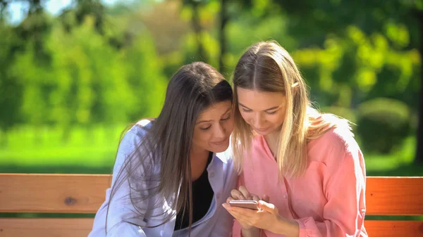 Молоді Жінки Дивитися Онлайн Відео Смартфоні Сидить Лавці Парку Додаток — стокове фото