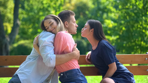 Boyfriend hugging girlfriend secretly kissing other woman, hidden relations