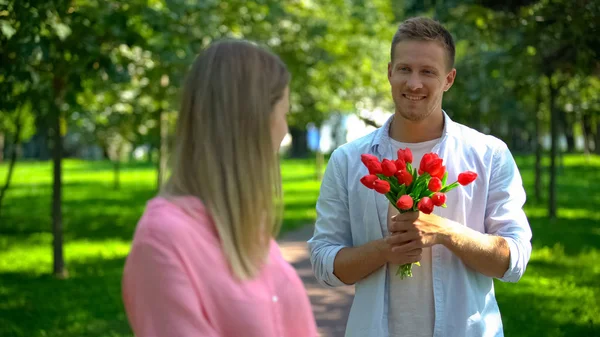 Beau Homme Souriant Avec Des Tulipes Rouges Regardant Petite Amie — Photo