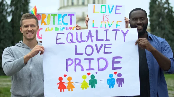 Man raising Equality love pride poster together with LGBT activists, pride march
