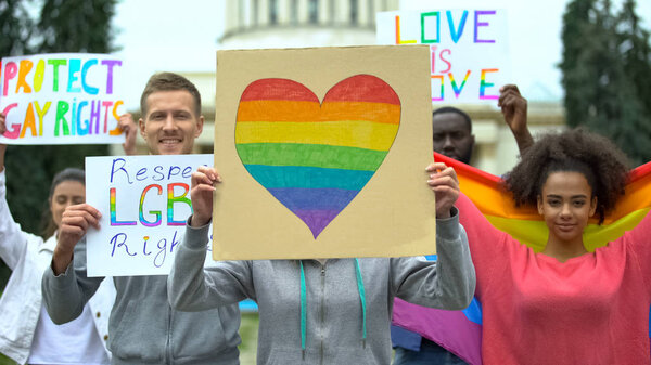LGBT activists holding posters with rainbow symbols, demanding equal rights