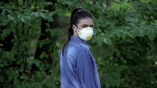 森の中に立っているカメラを見て保護マスクの女性 有害な化学物質 — ストック写真