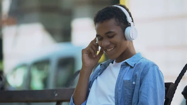 積極的な若者はヘッドフォンで音楽を聞いて 屋外のベンチに座って — ストック写真