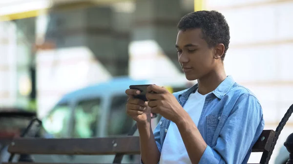 Aufgeregter Teenager Spielt Actionspiel Auf Smartphone Auf Bank Sitzend Sucht — Stockfoto