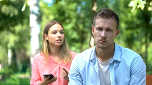Sad Young Man Looking Camera Annoyed Jealous Girlfriend Holding Phone Stock Photo
