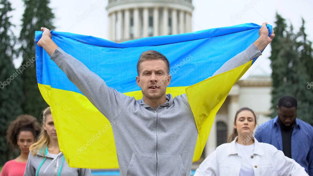 Activists raising Ukrainian flag chanting slogan, independence rally, patriotism