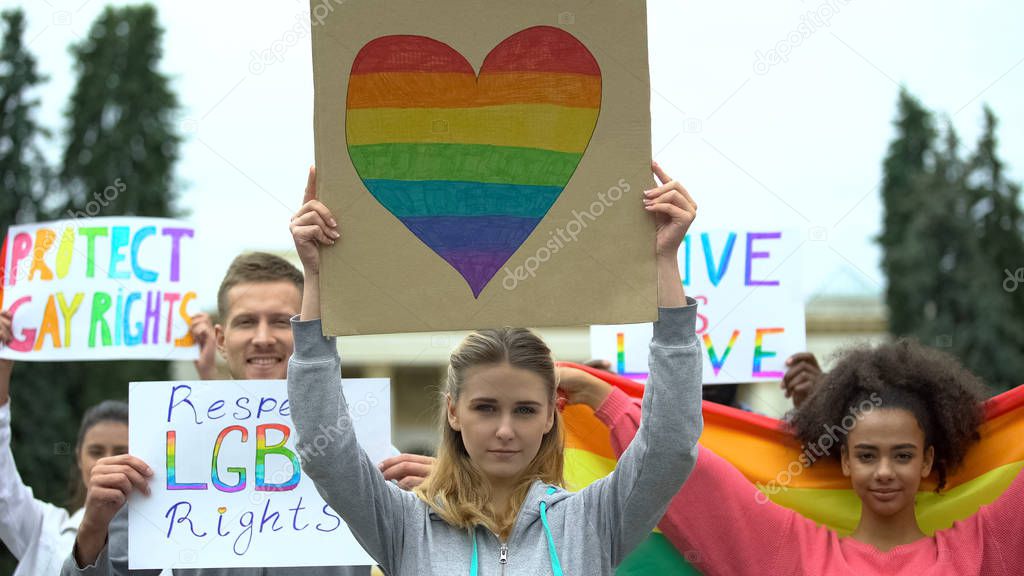 Activists raising posters and rainbow symbols, rally march for LGBT rights