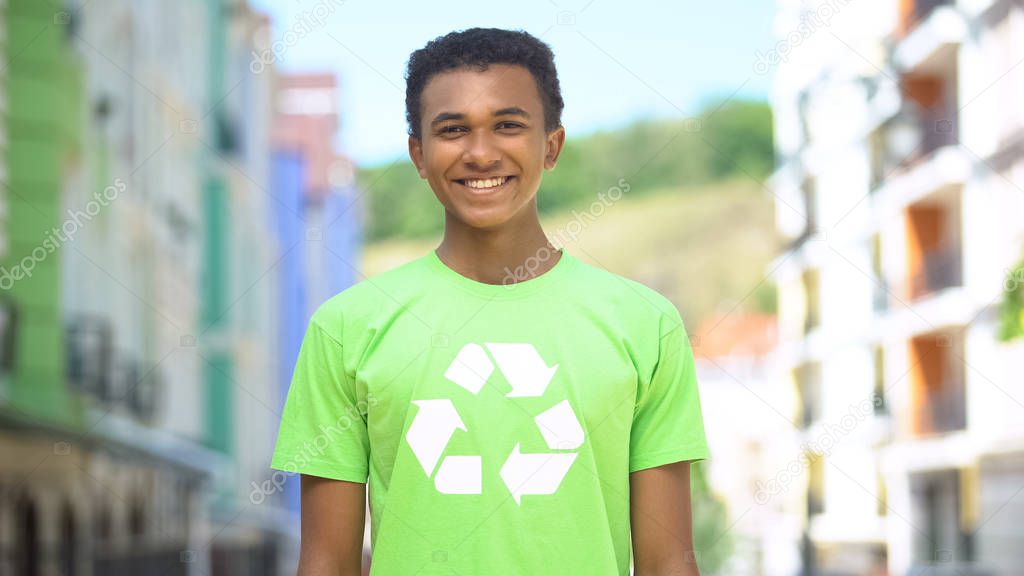 Cheery young eco-volunteer in recycling sign t-short smiling on cam, save nature