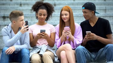 Genç adam arkadaşlarına yeni akıllı telefon fotoğrafı gösteriyor, alet bağımlılığı, gençlik