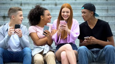 Neşeli kızıl saçlı öğrenci akıllı telefondan iyi haberler okuyor, online piyango.