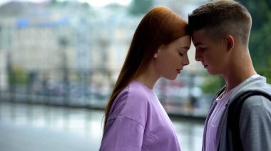 Genç çift yağmur şehir arka plan alınlarına dokunmadan birbirlerine bakıyor