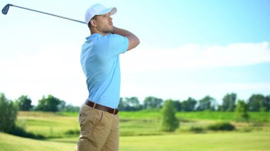 Deneyimli bir golfçü golf sahasında vuruşunu yapıyor, lüks bir hobi.
