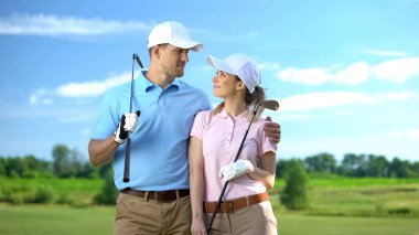 Young female and male with golf clubs hugging and smiling each other sport study clipart