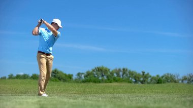 Profesyonel golfçü vuruşunu yapıyor, maçtan önce antrenman yapıyor.