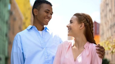 Positive mixed race couple looking at each other and laughing, togetherness clipart