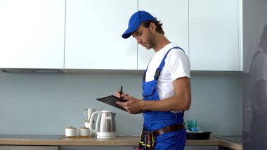 Aletleri olan bir adam mutfağı kontrol ediyor. Elektrik güvenliği, servis...