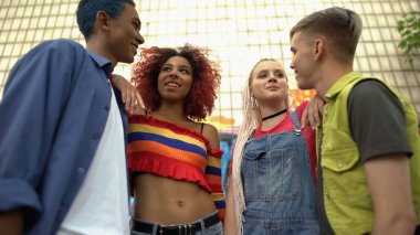 Çok ırklı gençlerden oluşan bir grup dışarıda konuşuyor, gençlerle iletişim kuruyor, dinleniyor.