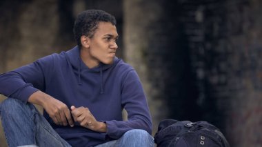 Akıllı telefon mesajını okuduktan sonra kızgın görünen Afrikalı bir genç. Aile sorunu.