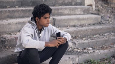 Depresif siyahi üniversite öğrencisi akıllı telefon müziği dinliyor, duygusal izolasyon