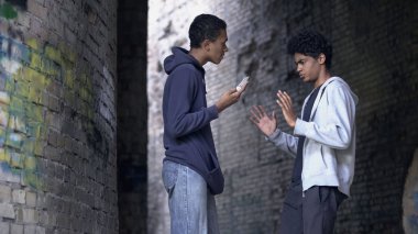Annoyed young male threatening with knife, teenage quarrel, dangerous city area