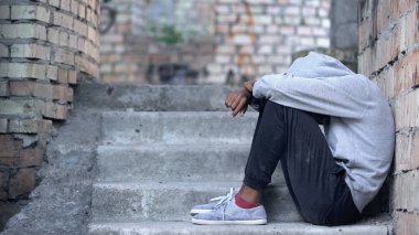 Yalnız genç erkek merdivenlerde oturuyor, yanlış anlaşılma depresyon, sorun