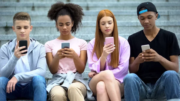 階段に座って スマートフォンをチャットする友人の十代のグループ — ストック写真