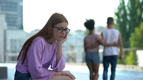 Deprimido Ruiva Adolescente Sentado Sozinho Durante Casal Amoroso Passando Rua — Fotografia de Stock