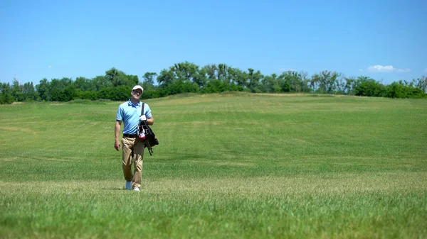 クラブバッグのレクリエーション活動でコースを歩く熟練した男性ゴルフトレーナー — ストック写真