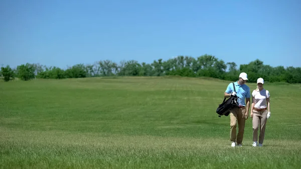 ゲーム趣味の後のコースウォーク中に通信するクラブバッグを持つゴルファーのペア — ストック写真
