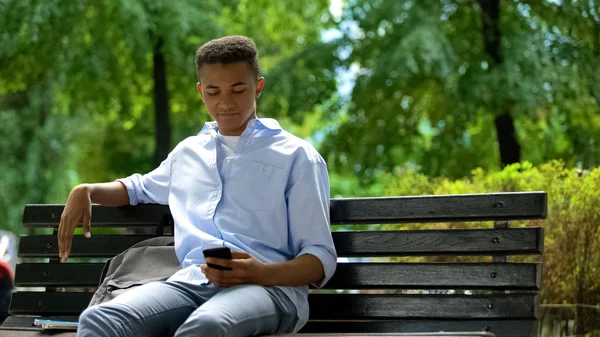 Giovane Smartphone Scorrimento Adolescente Seduto Sulla Panchina Nel Parco Procrastinazione — Foto Stock