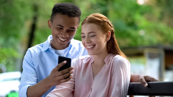 Sorrindo Casal Adolescentes Assistindo Fotos Smartphone Sentado Banco — Fotografia de Stock