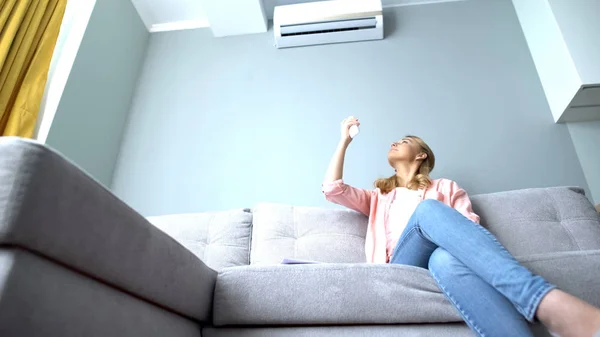 Cheerful girl turning on air conditioner, cooling and dehumidification mode