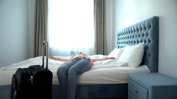 Avslappet Kvinne Med Koffert Liggende Stor Komfortabel Seng Hotellferie – stockfoto