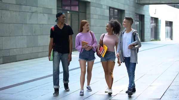 Multietniske Tenåringer Med Bøker Som Går Campus Friminuttet College stockbilde