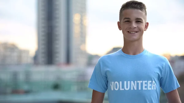 Glücklicher Gymnasiast Freiwilligen Shirt Lächelnde Kamera Humanitäre Hilfe lizenzfreie Stockfotos