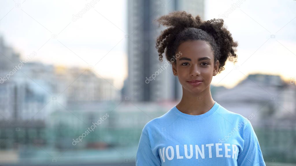 Black female volunteer looking camera, international charity foundation, support