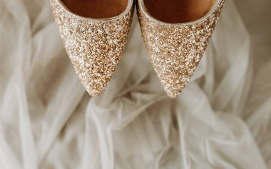 Sivri burunlu altın rengi tatil ayakkabıları arka planda bej tül kumaş, tatil düzeni, seçici odak