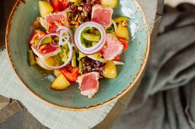 Güzel bir seramik mavi tabakta ızgara ton balıklı sebze salatası, güzel bir restoran yemeği, harika bir manzara.