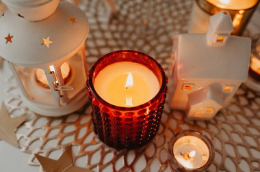 Noel ve Yeni Yıl için beyaz masa süslemesi, yanan beyaz ve kırmızı mumlar, hasır kahverengi peçete, çelenkler ve sıcak bir ışık şeklinde fener.