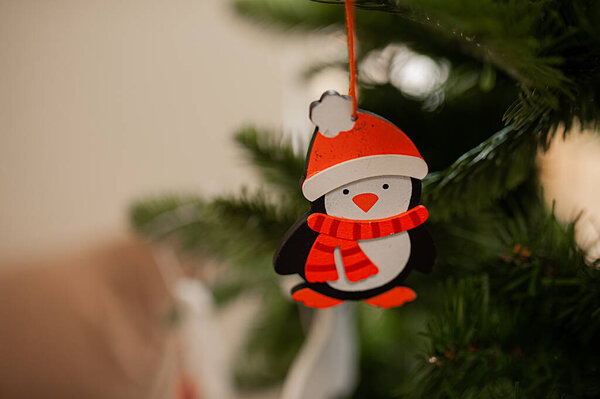 деревянная экологически чистая игрушка для елки в виде пингвина в красной шляпе крупным планом