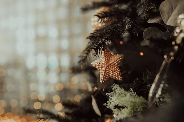 Christmas decoration on a Christmas tree in the form of a golden star in garlands and yellow bokeh