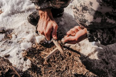 Kaba derisi olan kirli eller ellerinde keskin bir bıçak tutarlar ve onunla küçük bir tahta parçası keserler.